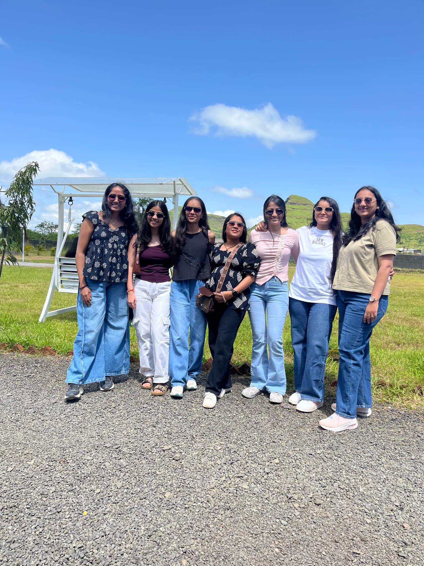 Engross colleagues posing together outdoors with green hills behind them